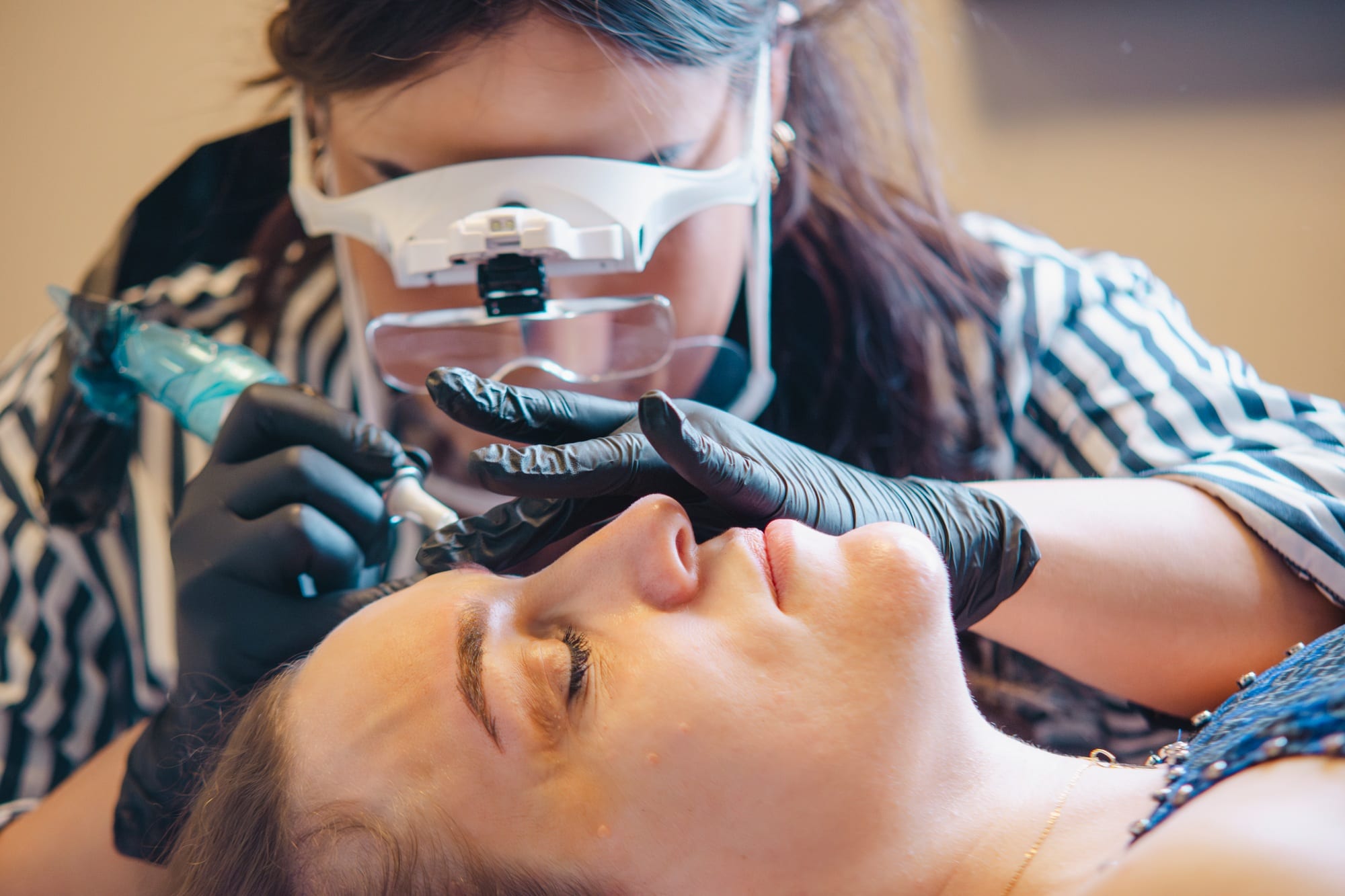 Beautician applying permanent makeup on eyebrows in beauty salon