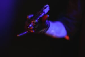 Closeup of tattooer master's hand in black glove holding machine for making tattoo art